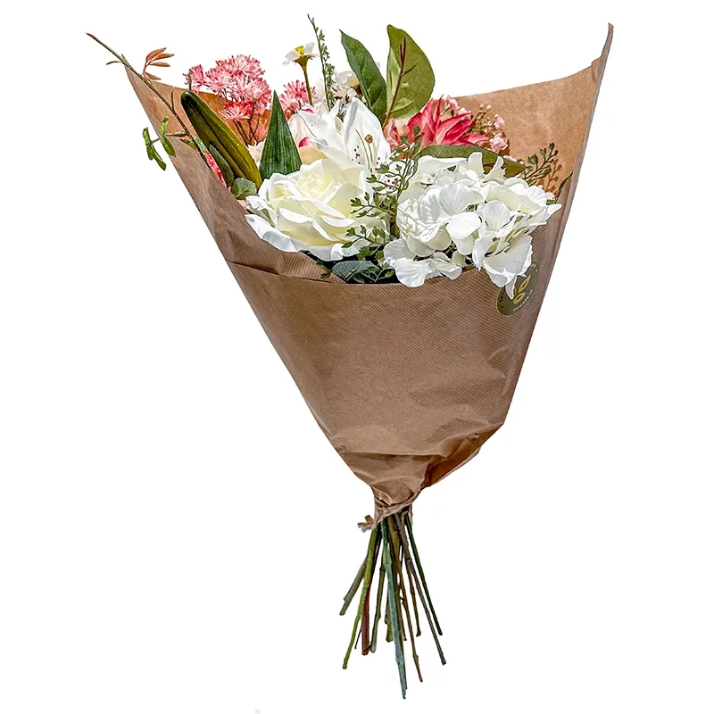 Smuk kunstig buket i hvide og lyserøde farver af forskellige kunstige blomster pakket fint ind i blomsterpapir