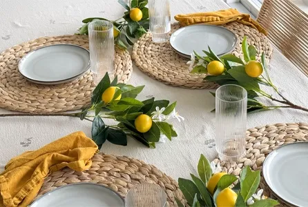 Bord dækket kunstige citrongrene mellem tallerkner og glas