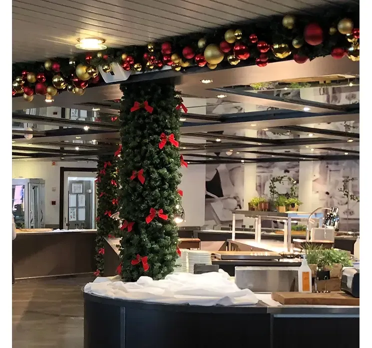 Kunstig granranke imperial af plast i grøn vist i miljø med julekugler og røde sløjfer 