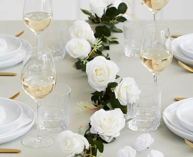 Kunstig blomsterranke af hvid roser på et bryllupsbord